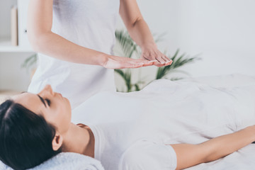 Obraz na płótnie Canvas cropped shot of peaceful young woman receiving reiki healing treatment