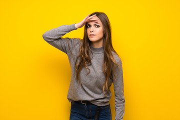 Naklejka premium Young woman over yellow wall looking far away with hand to look something