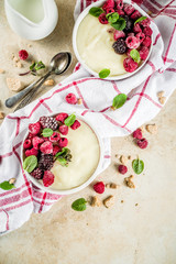 Two bowl with Semolina porridge with fresh berries, beige stone table copy space top view