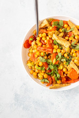 Curry with chickpea, turkey, carrot, leek and dried apricots in a white plate. Healthy food. Concrete background. Copy space.