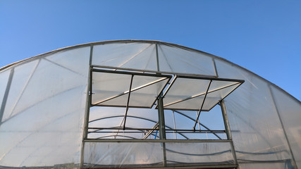 view to the greenhouse with door or windows for  maintaining the microclimate, humidity and temperature for optimal growth of greenhouse plants , in sunny day, horizontal