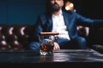 Glass of brandy and cuban cigar on an old wooden table. © opolja