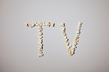 Obraz premium flat lay of tasty popcorn with tv lettering isolated on white