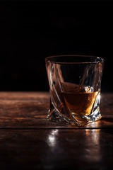 close-up view of brandy in glass on wooden table on black