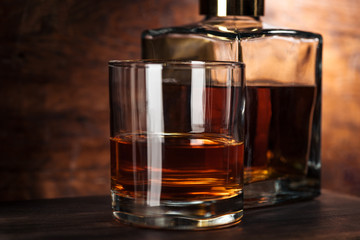 close-up view of glass of whiskey and bottle on wooden table