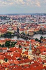 The panoramic view of Prague from the observation desk of Cathedral churh of St. Vitus, Czech Republic. Red roofs, churches, the Charles Bridge and the Vltava river. Cloudy rainy day. 