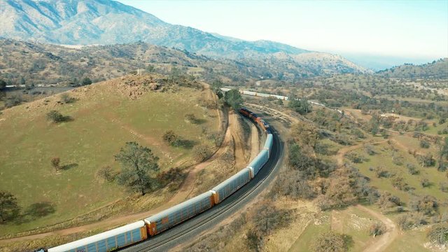 A freight train comes around the northern corner of the Tehachapi Rail Loop Cross Hill. The aerial drone follows farther back from the locomotives.
