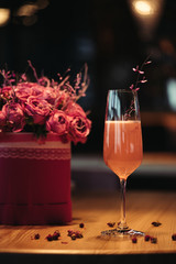 selective focus of pink alcoholic cocktail with flowers on dark background
