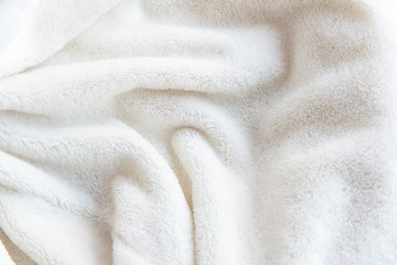 White delicate soft  background of plush fabric. Texture of beige soft fleecy blanket textile with...