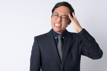 Portrait of stressed Japanese businessman in suit having headache
