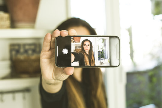 Woman making a selfi with serious expression.Woman taking a picture with her mobile phone.