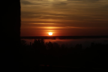 Red sunrise on fog background. Sun over the forest