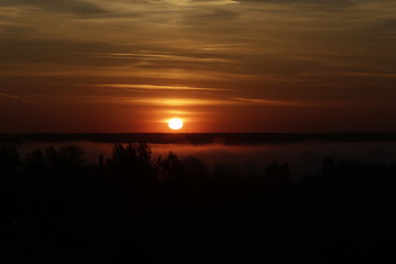 Red sunrise on fog background. Sun over the forest