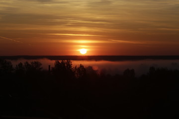 Red sunrise on fog background. Sun over the forest
