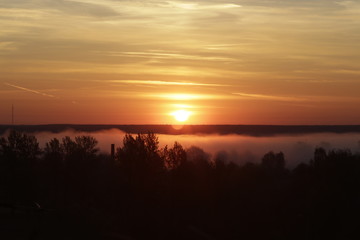 Red sunrise on fog background. Sun over the forest