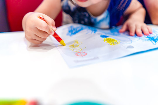 Kid play, study and learn how to color and draw the crayon color in to the paper with her parents.
