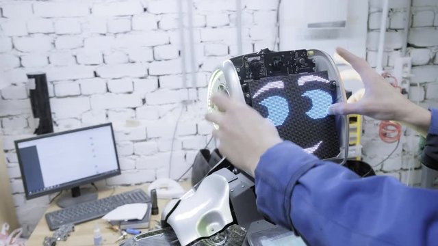 Factory for the production of robots. The scientist inserts the board - the face of the robot. Gives life to the robot.
