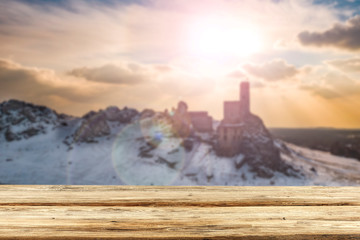Fototapeta premium Winter landscape with an old castle and a wooden table with a free place for an advertising product among rocks 