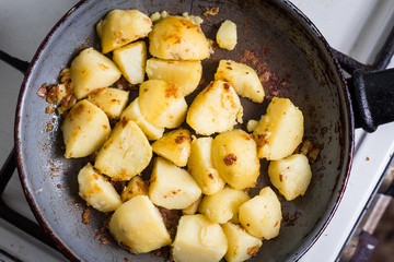 A cut potato fries on a heated pan