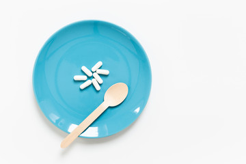 Pills on Plate and wooden spoonk on White Background