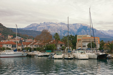 Fototapeta na wymiar Beautiful Mediterranean landscape on cloudy winter day. Montenegro, Bay of Kotor. View of Marina Kalimanj in Tivat city and peaks of Lovcen mountains