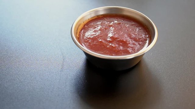 Red sauce in metal plate on black background fried snack combo slow motion
