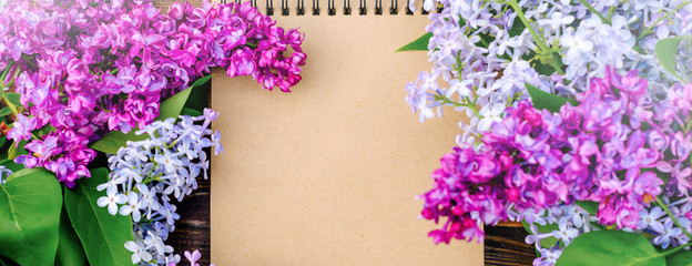 Banner top view of the purple lilac flowers branch on a wooden background. Bunches of small flowers. Place for your text.
