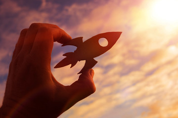 rocket in the hand of a man on the background of the evening sky. the aspiration of upward growth.