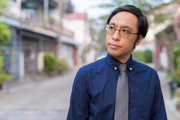 Obraz premium Face of Japanese businessman with eyeglasses thinking outdoors