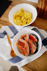 Portions of fresh salmon fillet with aromatic herbs and spices in a bowl on the table in the kitchen