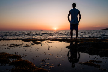 Fototapeta premium man looks at the sunset at the sea