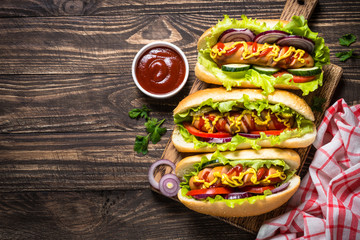 Hot dog with fresh vegetables on wooden table.