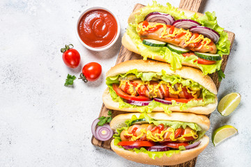 Hot dog with fresh vegetables on white top view.