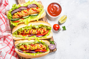 Hot dog with fresh vegetables on white top view.