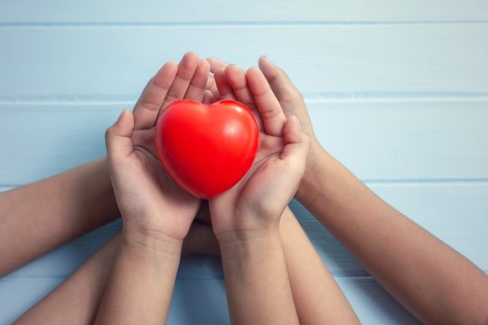 Child hands holding red heart