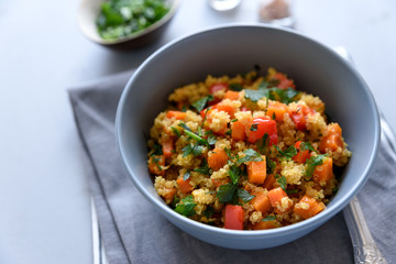 Healthy vegan bowl with quinoa, pumpkin, pepper and carrot on gray wooden background. Selective focus