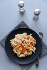 Tasty vegetarian pilaf with rice, carrot and chickpeas on gray wooden background. Copy space. Top view. Selective focus