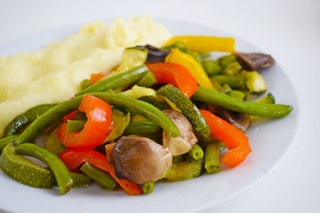 Mashed potatoes and vegetables with mushrooms on a white plate.