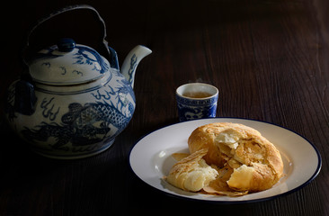 Chinese pastry in white dish with Chinese tea and teapot on dark wooden background which has dim light