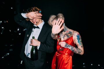 couple covering face while holding alcohol drinks on party isolated on black