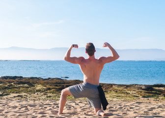 young muscular guy posing on a ocean background