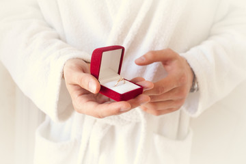 Marriage proposal. The hand holds a red gift box with a gold ring. Sentence. The best day. Gives a ring. Closeup