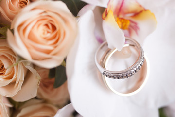 two gold wedding rings lie on a bouquet of flowers, close-up