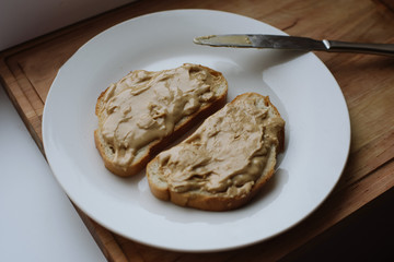 Delicious peanut butter sandwich breakfast on white plate, wooden table background. Sweet food, breakfast concept