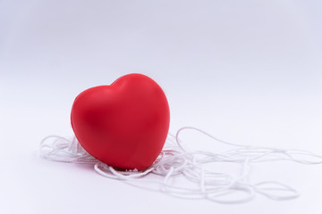 Red heart ball put on white rope,white background. tall tie love and care health.