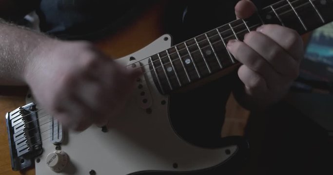 Naturally lit close up shot of a young guitarist rapidly playing a solo with intense feeling.