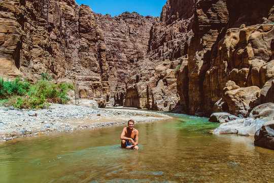 Young adventurous man in Wadi Zarqa Ma'in canyon located in the mountainous landscape to the east of the Dead Sea, near to Wadi Mujib, Jordan, Middle East