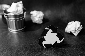 recycle symbol surrounded by scrunched paper balls with garbage bin
