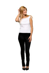 Fototapeta premium Young blonde woman thinking an idea while scratching head over isolated white background