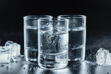 Cold vodka in shot glasses on a black background. - obrazy, fototapety, plakaty